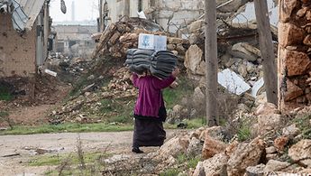 Eine Frau trägt von der UNHCR bereitgestellte Decken