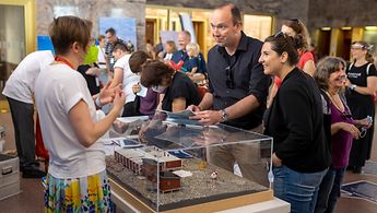 Eine Mitarbeiterin des Auswärtigen Amts beantwortet Besucherinnen und Besuchern an einem Stand Fragen zum Auswärtigen Amt