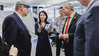 Außenministerin Baerbock lässt sich ein technisches Gerät des Weltraumzentrums der Universität Auckland erklären